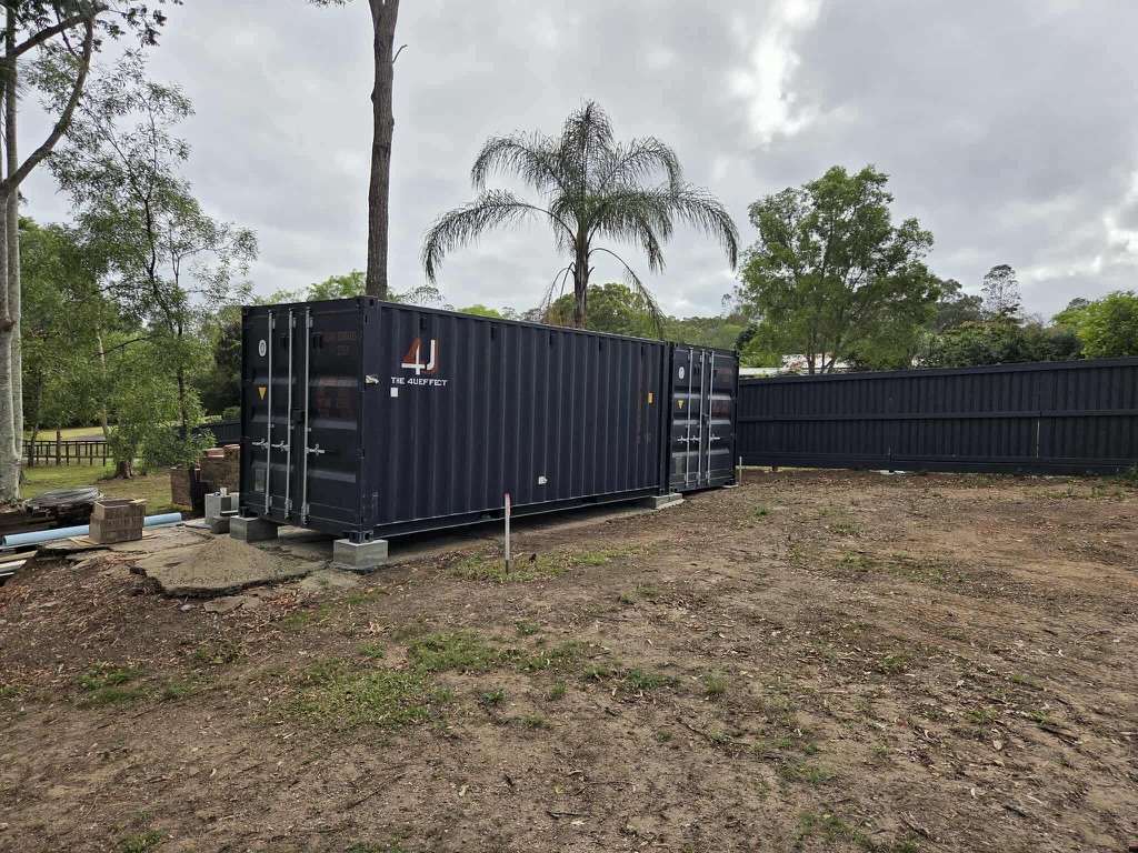 Two 20ft shipping containers placed on a prepared spot in a private yard