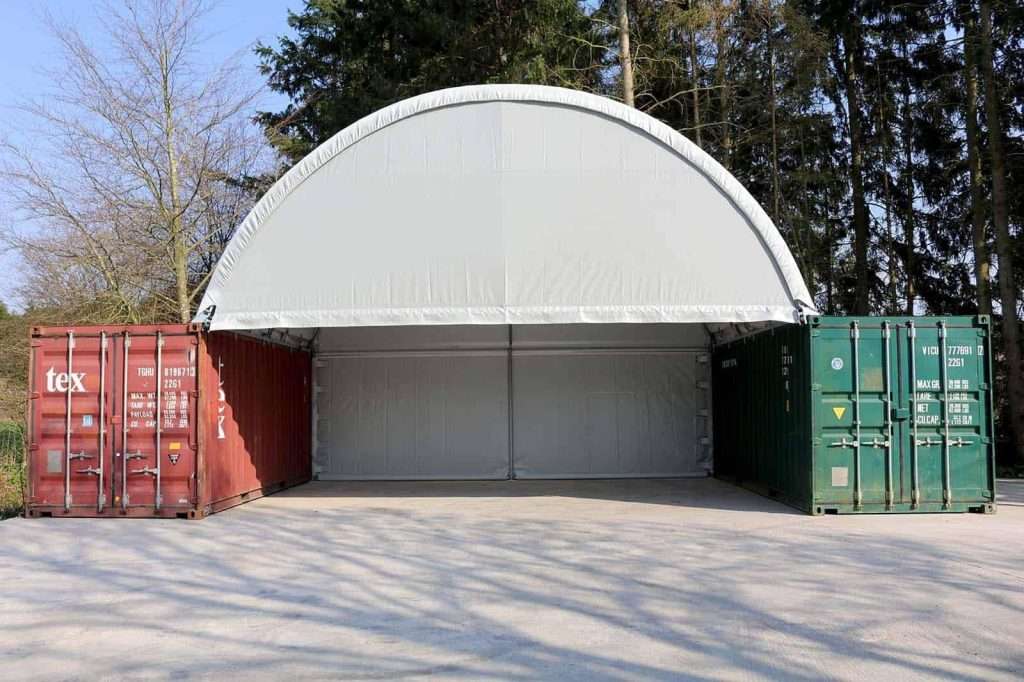 Two 40ft shipping containers with an arched roof between them as a covered garage