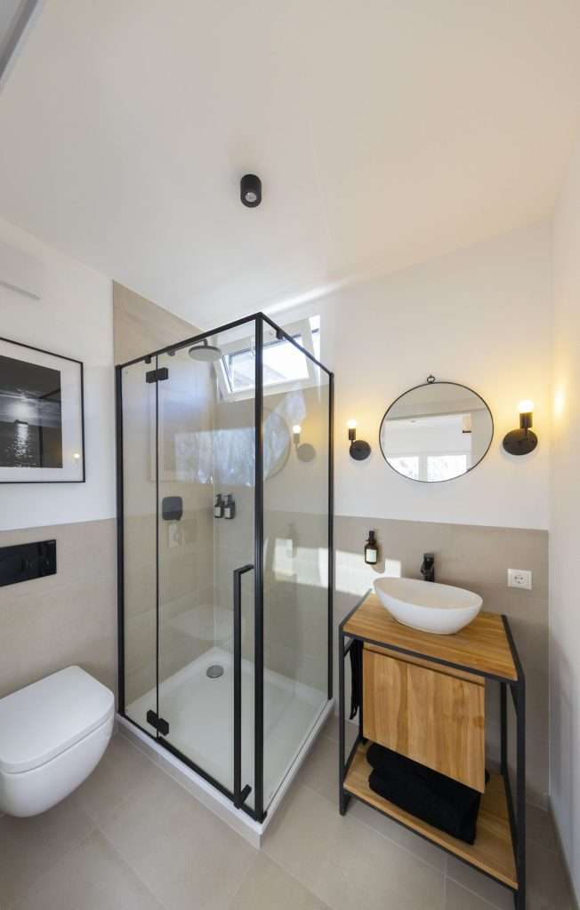 Bathroom with glass shower and wooden vanity inside a container home
