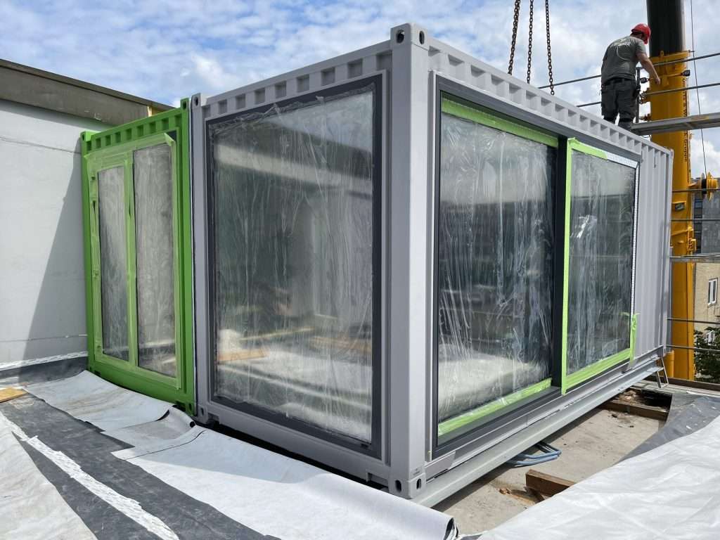 Container module with glass in protective film being set down on a roof