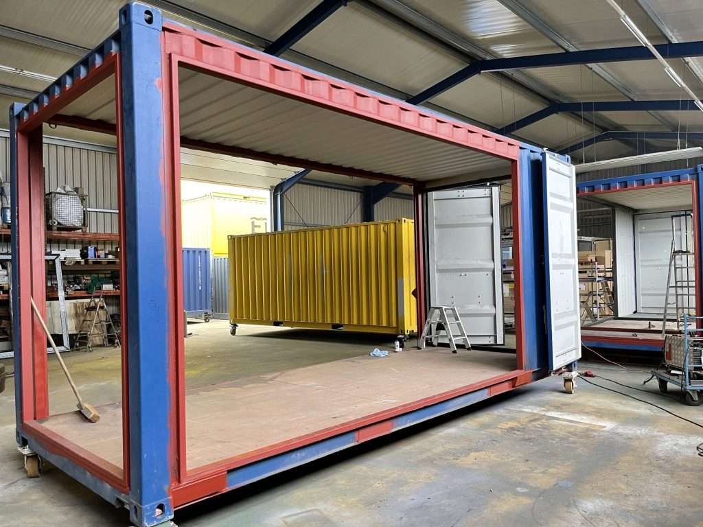 Shipping container with the side wall cut out and a steel frame around the opening