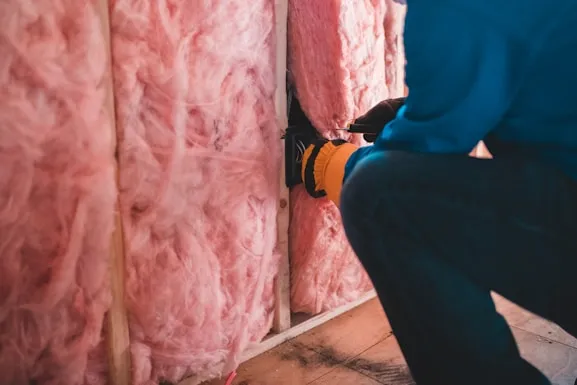 Installing pink insulation inside a shipping container wall
