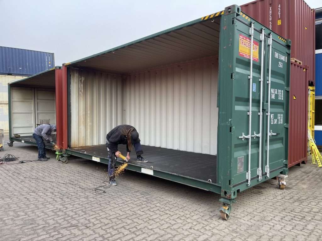Workers cutting the side wall out of a 40ft shipping container with grinders