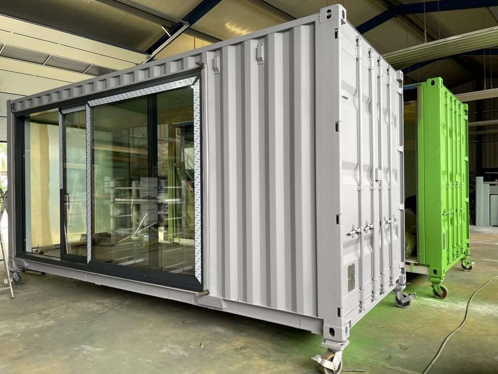 White shipping container with sliding glass doors in a workshop